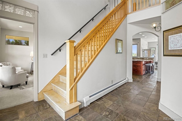 staircase featuring a baseboard heating unit and carpet floors