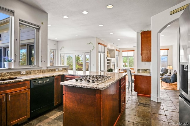 kitchen with a textured ceiling, a healthy amount of sunlight, stainless steel appliances, and a kitchen island