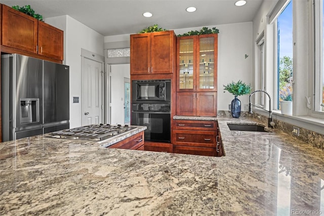 kitchen with appliances with stainless steel finishes, sink, and light stone counters