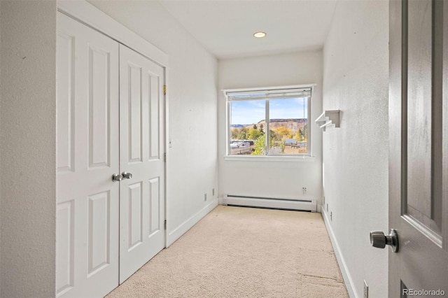 unfurnished bedroom featuring baseboard heating and light colored carpet