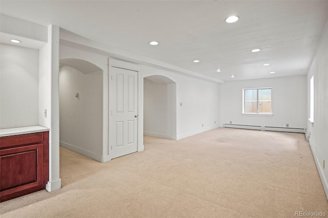 carpeted empty room featuring a baseboard heating unit