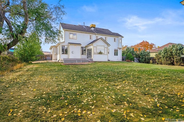 rear view of house featuring a wooden deck and a yard