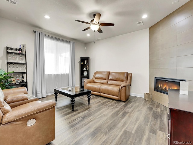 9844 Truckee St, Commerce City, CO 80022 - living room with a tiled fireplace, visible vents, recessed lighting, wood finished floors, and ceiling fan