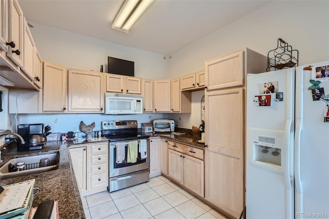 kitchen with light tile patterned floors, white appliances, sink, and dark stone counters