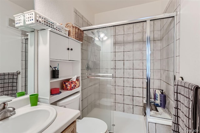 bathroom with vanity, a shower with shower door, and toilet