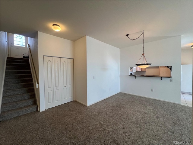 unfurnished living room featuring stairs and carpet
