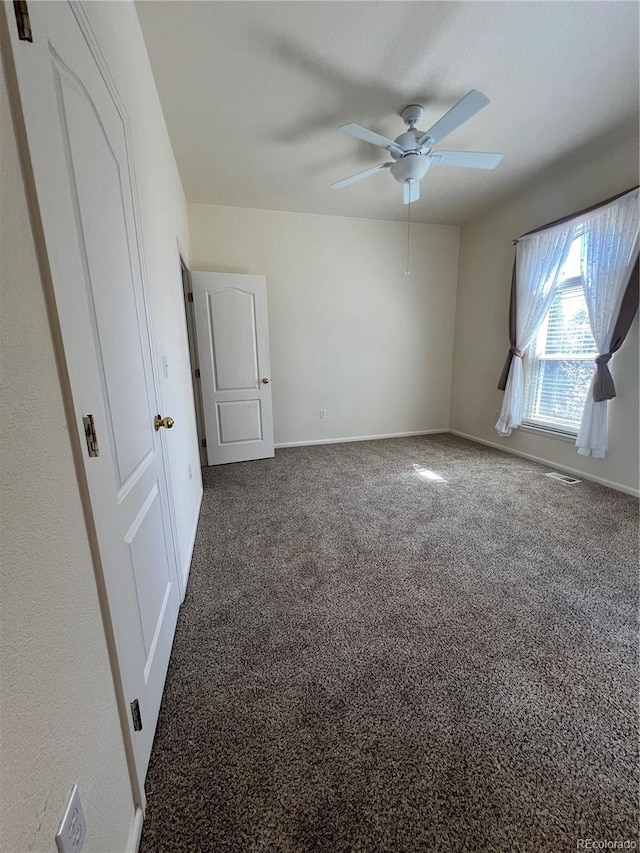 spare room with carpet, baseboards, and a ceiling fan