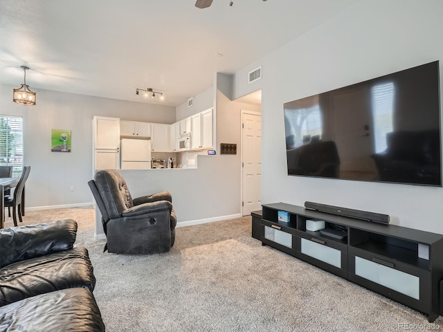 living area with visible vents, track lighting, baseboards, light carpet, and ceiling fan with notable chandelier