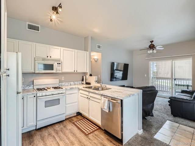 kitchen with white appliances, visible vents, a peninsula, a sink, and open floor plan