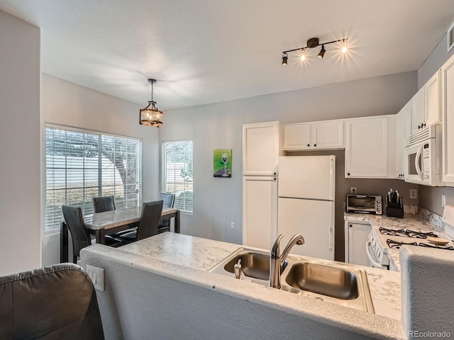 kitchen with a toaster, pendant lighting, white appliances, white cabinetry, and a sink