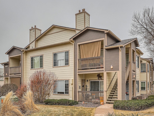 view of front of property with stairway, a balcony, covered porch, and a chimney