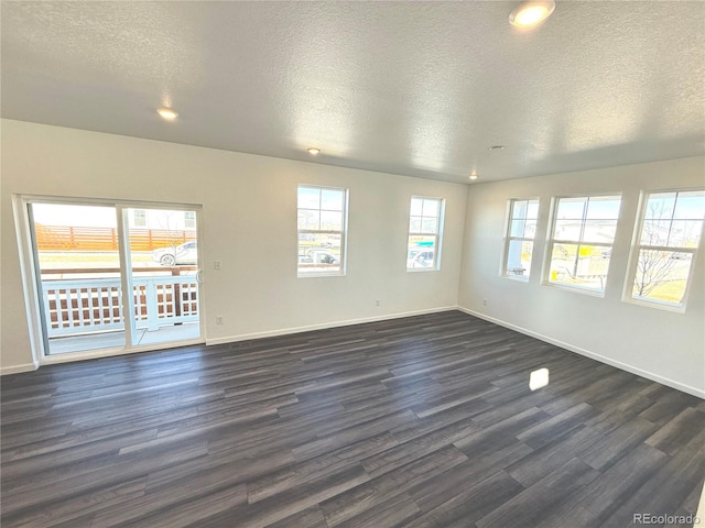 empty room with dark hardwood / wood-style flooring and a textured ceiling