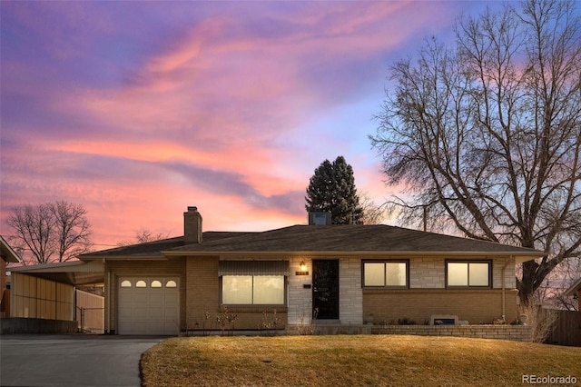 view of front facade with a garage, a yard, and a carport