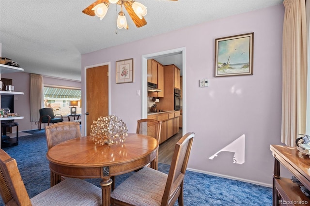 carpeted dining area with a textured ceiling and ceiling fan