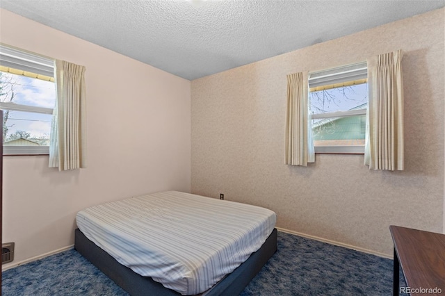 bedroom with a textured ceiling and dark carpet