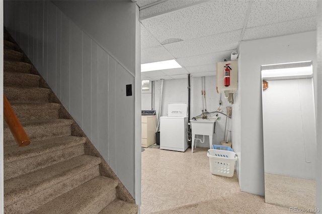 basement with sink, a paneled ceiling, and washer and dryer