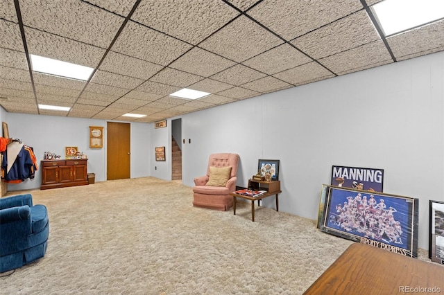 living area featuring a drop ceiling and carpet