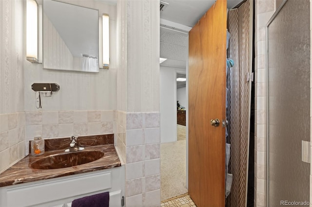 bathroom with tile walls, vanity, and walk in shower