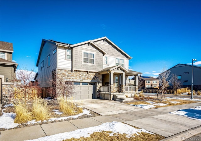 view of front of home with a porch, an attached garage, stone siding, concrete driveway, and a residential view