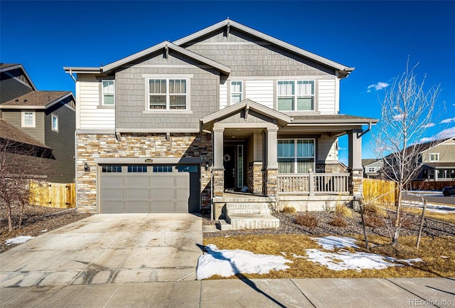 craftsman-style house featuring concrete driveway, stone siding, an attached garage, covered porch, and fence