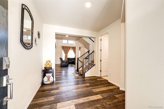 corridor featuring baseboards, stairway, and wood finished floors