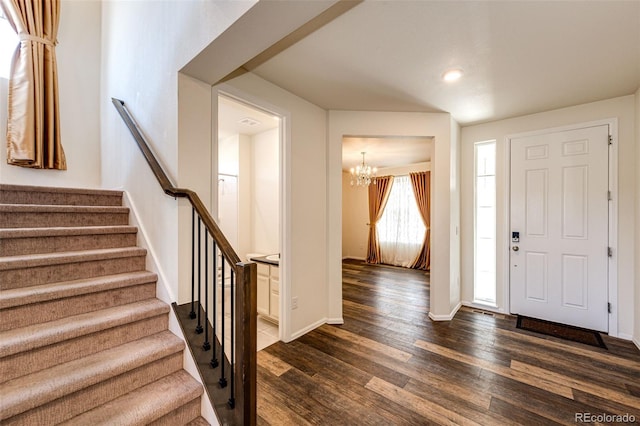 foyer with a notable chandelier, stairs, baseboards, and dark wood-style flooring