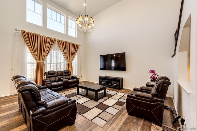 living area with baseboards, a high ceiling, a chandelier, and wood finished floors