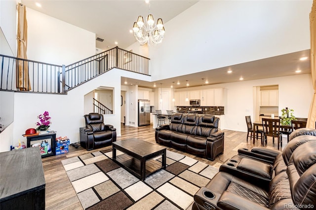 living room featuring a chandelier, stairs, light wood-style flooring, and recessed lighting