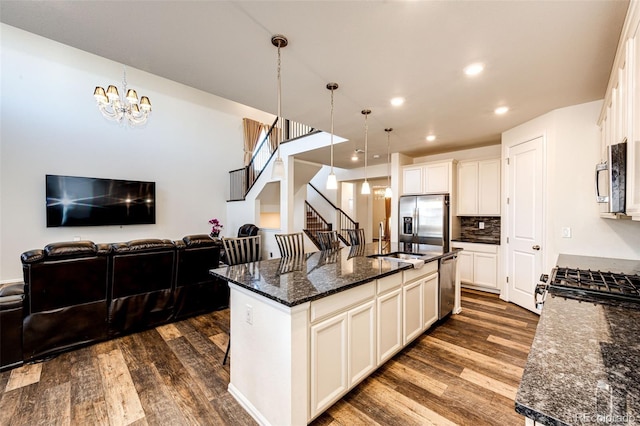 kitchen featuring dark wood-style floors, stainless steel appliances, open floor plan, a sink, and a chandelier