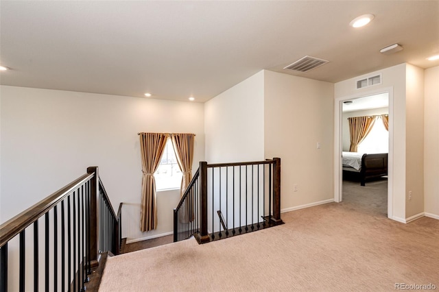 hallway with carpet floors, recessed lighting, visible vents, and an upstairs landing