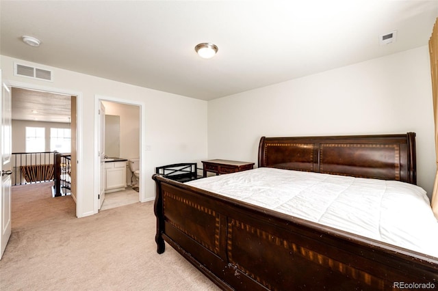 bedroom with visible vents, connected bathroom, light carpet, and baseboards