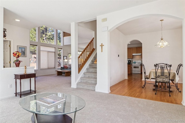 living area with carpet, recessed lighting, stairway, an inviting chandelier, and baseboards