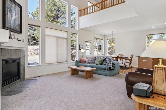 living area featuring plenty of natural light, carpet, visible vents, and a tiled fireplace