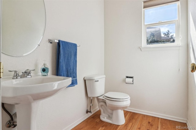 half bathroom with a sink, wood finished floors, toilet, and baseboards