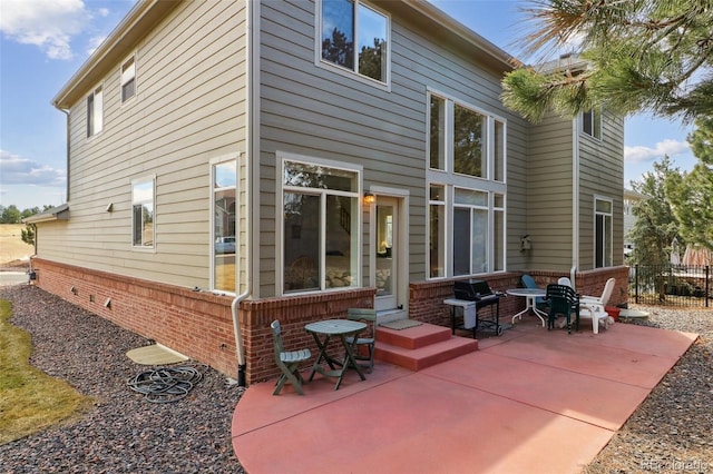 rear view of property with brick siding, fence, and a patio