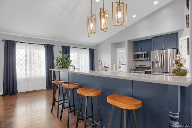 kitchen with blue cabinetry, stainless steel appliances, vaulted ceiling, a kitchen bar, and decorative backsplash