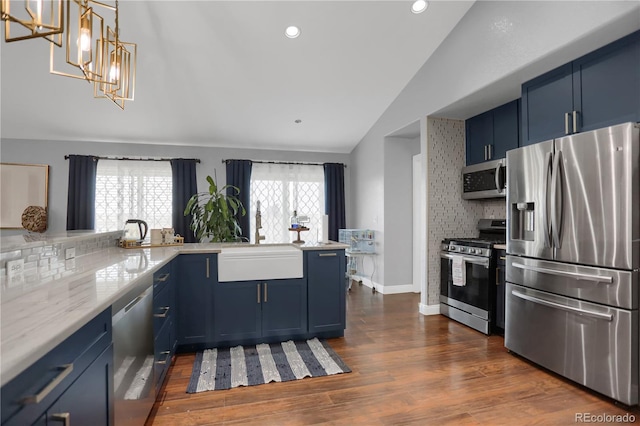 kitchen featuring kitchen peninsula, backsplash, stainless steel appliances, blue cabinets, and sink