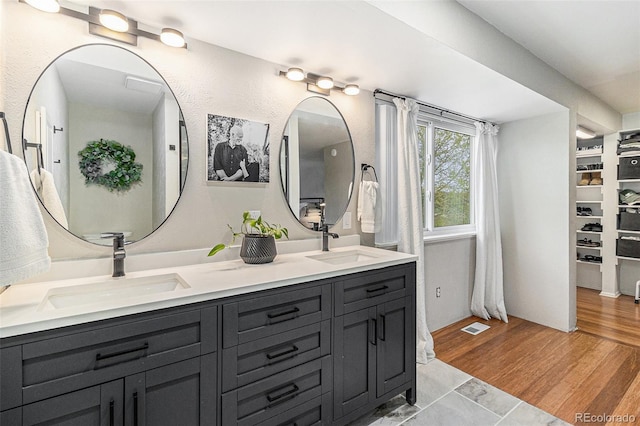 6731 Devinney St, Arvada, CO 80004 - bathroom with double vanity, wood finished floors, and a walk in closet