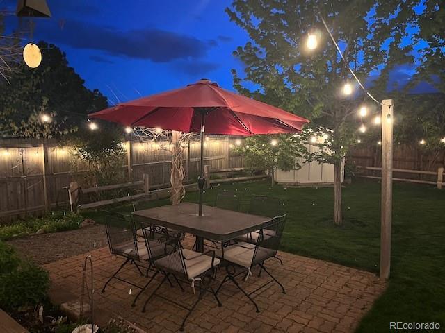 6731 Devinney St, Arvada, CO 80004 - patio at twilight featuring outdoor dining area and a fenced backyard
