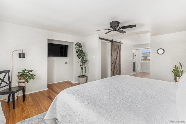 6731 Devinney St, Arvada, CO 80004 - bedroom with a barn door, wood finished floors, baseboards, and a ceiling fan