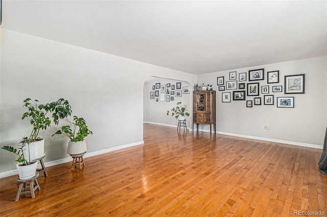 6731 Devinney St, Arvada, CO 80004 - spare room featuring arched walkways, light wood finished floors, and baseboards