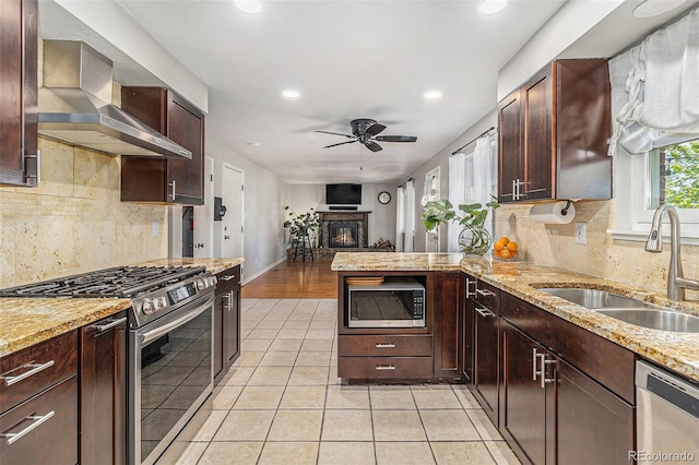 6731 Devinney St, Arvada, CO 80004 - kitchen featuring stainless steel appliances, wall chimney range hood, a sink, ceiling fan, and light tile patterned floors