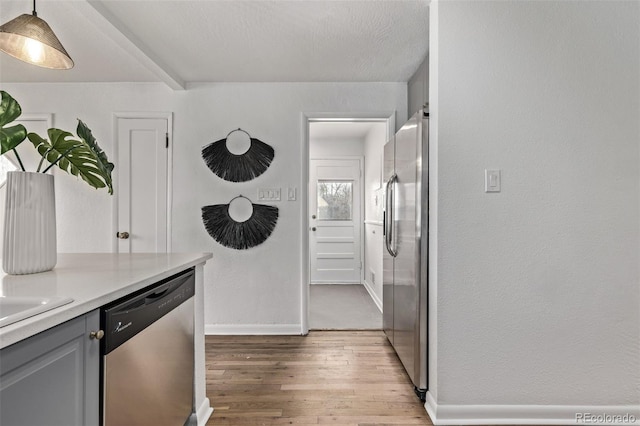 6133 S Sterne Cir, Littleton, CO 80120 - kitchen with appliances with stainless steel finishes, light countertops, gray cabinets, baseboards, and light wood-type flooring