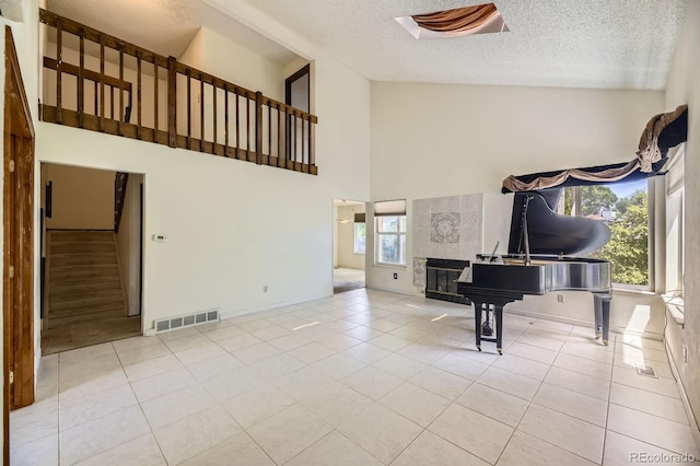 2370 Redwood Ave, Lafayette, CO 80026 - living area featuring high vaulted ceiling, stairs, tile patterned floors, a tile fireplace, and a textured ceiling