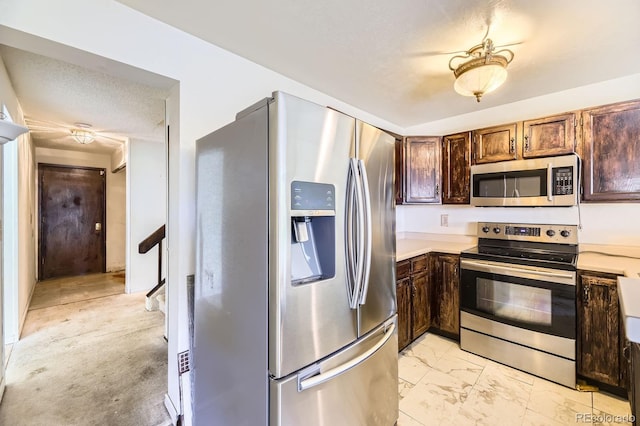 2370 Redwood Ave, Lafayette, CO 80026 - kitchen featuring appliances with stainless steel finishes, light marble finish flooring, a textured ceiling, light countertops, and dark brown cabinets