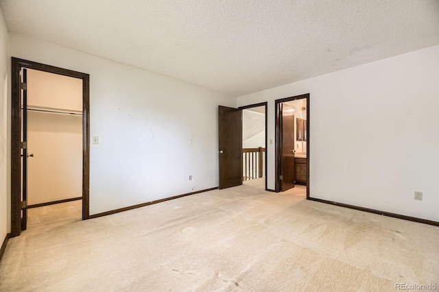 2370 Redwood Ave, Lafayette, CO 80026 - unfurnished bedroom featuring light carpet, a walk in closet, a textured ceiling, a closet, and ensuite bath