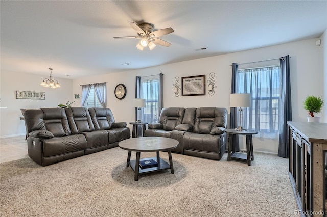 carpeted living room with ceiling fan with notable chandelier