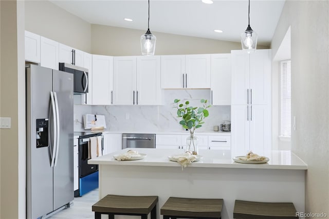 kitchen with a kitchen bar, white cabinets, appliances with stainless steel finishes, and light countertops