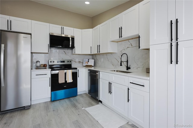 kitchen featuring light wood-style flooring, a sink, white cabinetry, stainless steel appliances, and light countertops