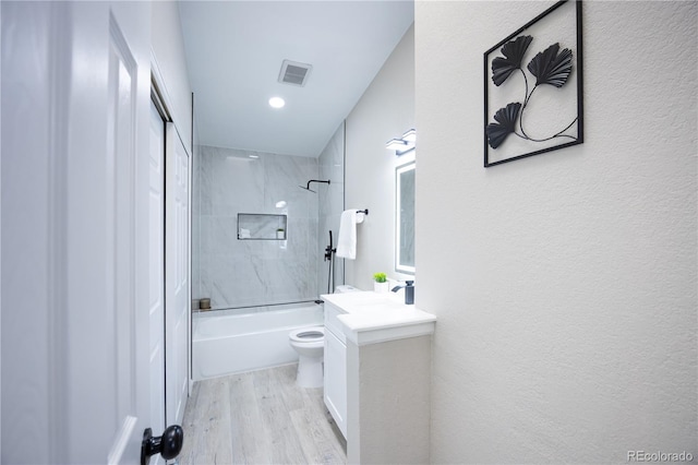 bathroom featuring vanity, wood finished floors, tub / shower combination, toilet, and a textured wall